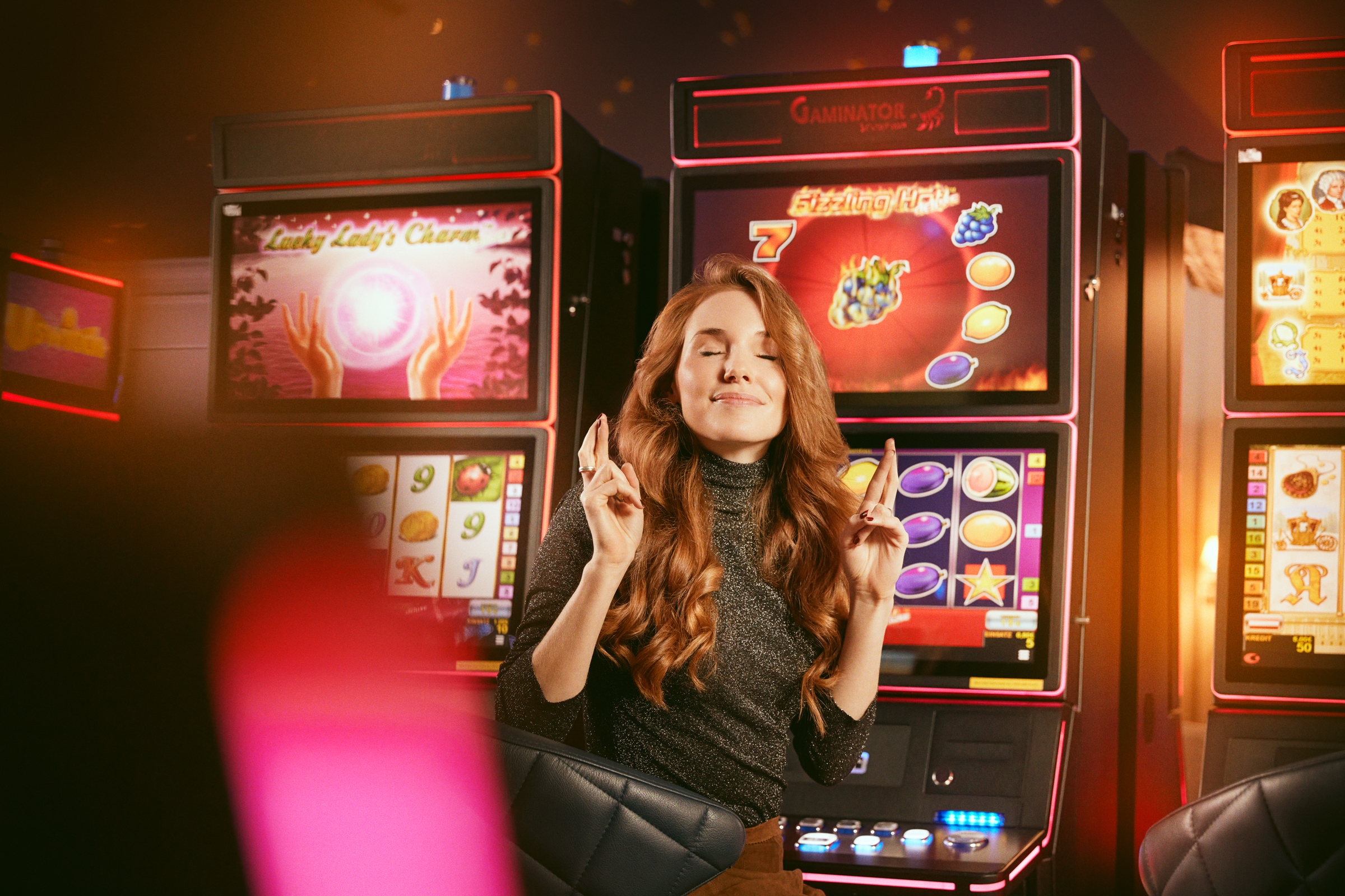 Casinos Austria Dame mit gekreuzten Fingern vor den Spielautomaten