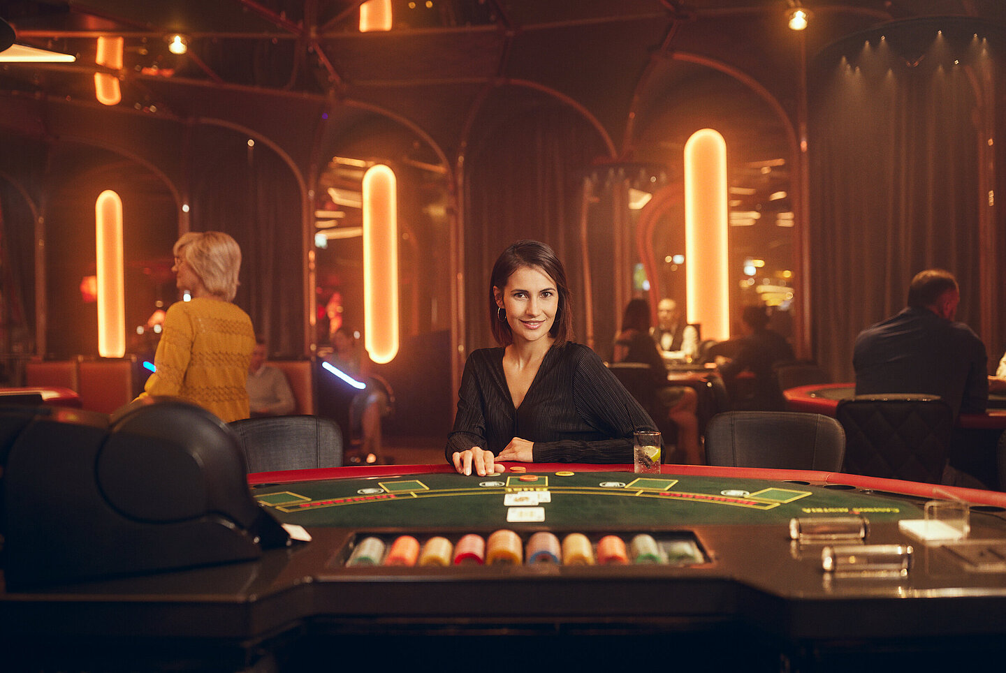 Dunkelhaarige Dame sitzt am Black Jack Tisch im Casino