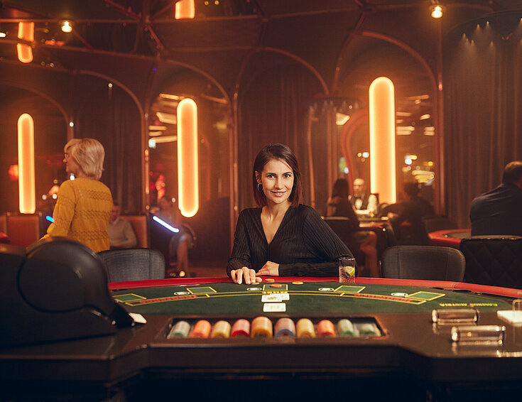 Dunkelhaarige Dame sitzt am Black Jack Tisch im Casino