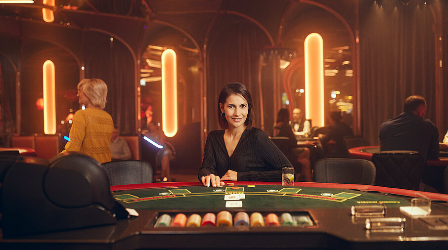 Dunkelhaarige Dame sitzt am Black Jack Tisch im Casino