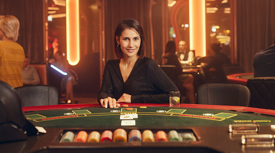 Dunkelhaarige Dame sitzt am Black Jack Tisch im Casino