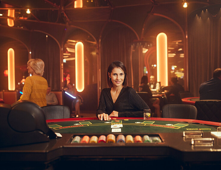 Casinos Austria Dunkelhaarige Dame sitzt am Black Jack Tisch im Casino