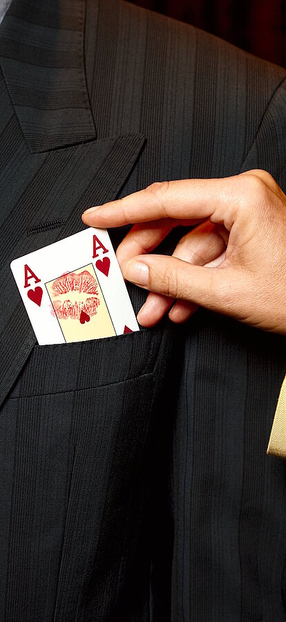 Damen-Hand steckt Herz-Ass Spielkarte einem Herrn ins Sakko
