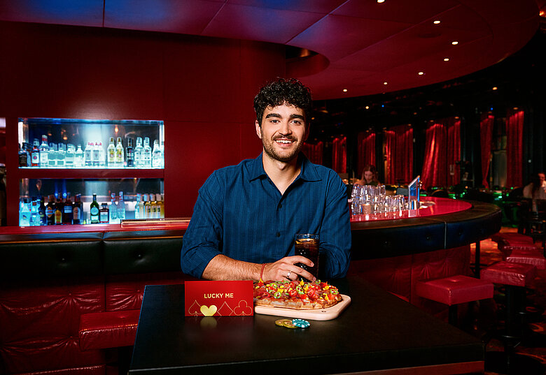 Mann an der Casino Bar mit Lucky Me Gutschein, Pinsa und Cola