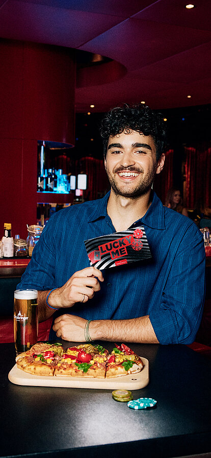 Mann an der Casino Bar mit Lucky Me Gutschein, Pinsa und Cola