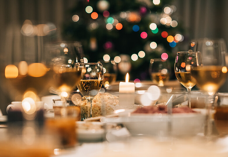Festlich gedeckter Weihnachts-Dinner-Tisch mit Christbaum im Hintergrund