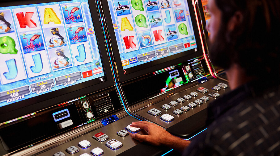 Mann sitzt vor einem Spielautomat im Casino