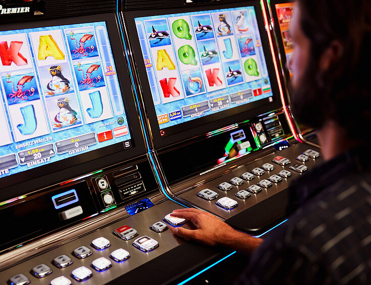 Casinos Austria Mann sitzt vor einem Spielautomat im Casino