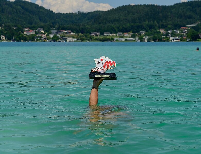 Poker EM 2025 Sujet Hand mit Pokal im Wörthersee