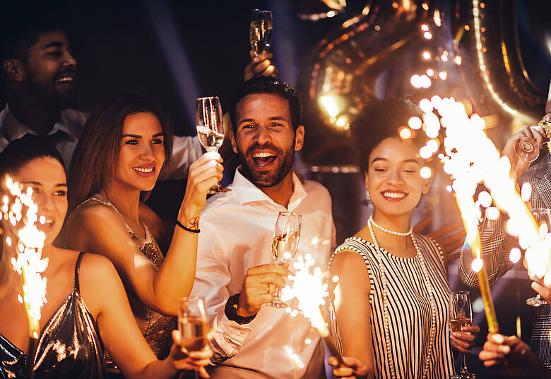 Gruppe von Menschen feiern Silvester mit Sekt und Wunderkerzen