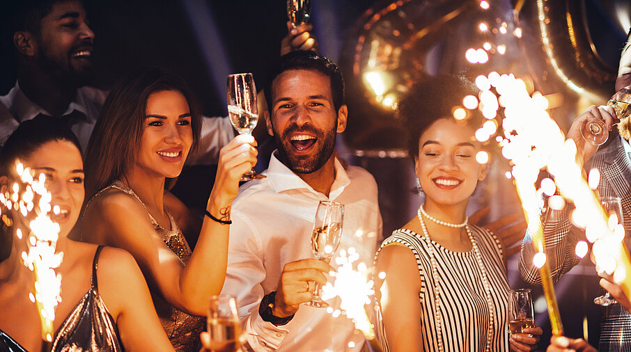Gruppe von Menschen feiern Silvester mit Sekt und Wunderkerzen