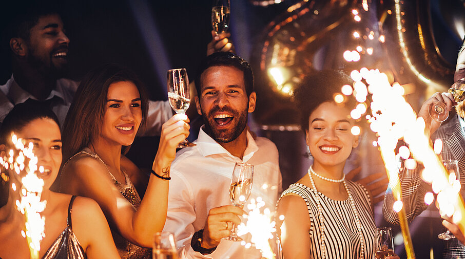 Gruppe von Menschen feiern Silvester mit Sekt und Wunderkerzen
