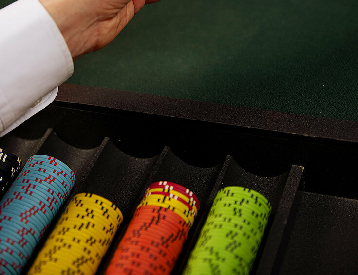 Dealer-Hände mit zwei Poker-Karten: Zehn und Drei am Poker-Tisch mit Jetons