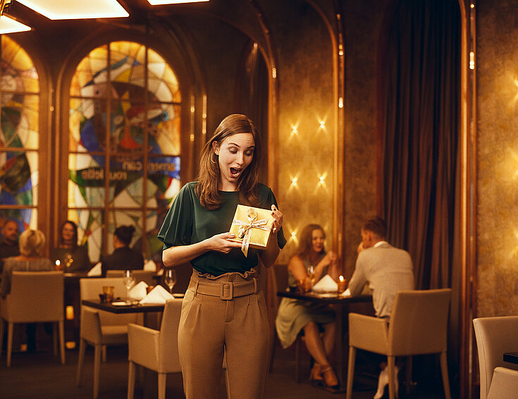 Casinos Austria Staunende Dame mit goldenem Geschenk im Casino Restaurant