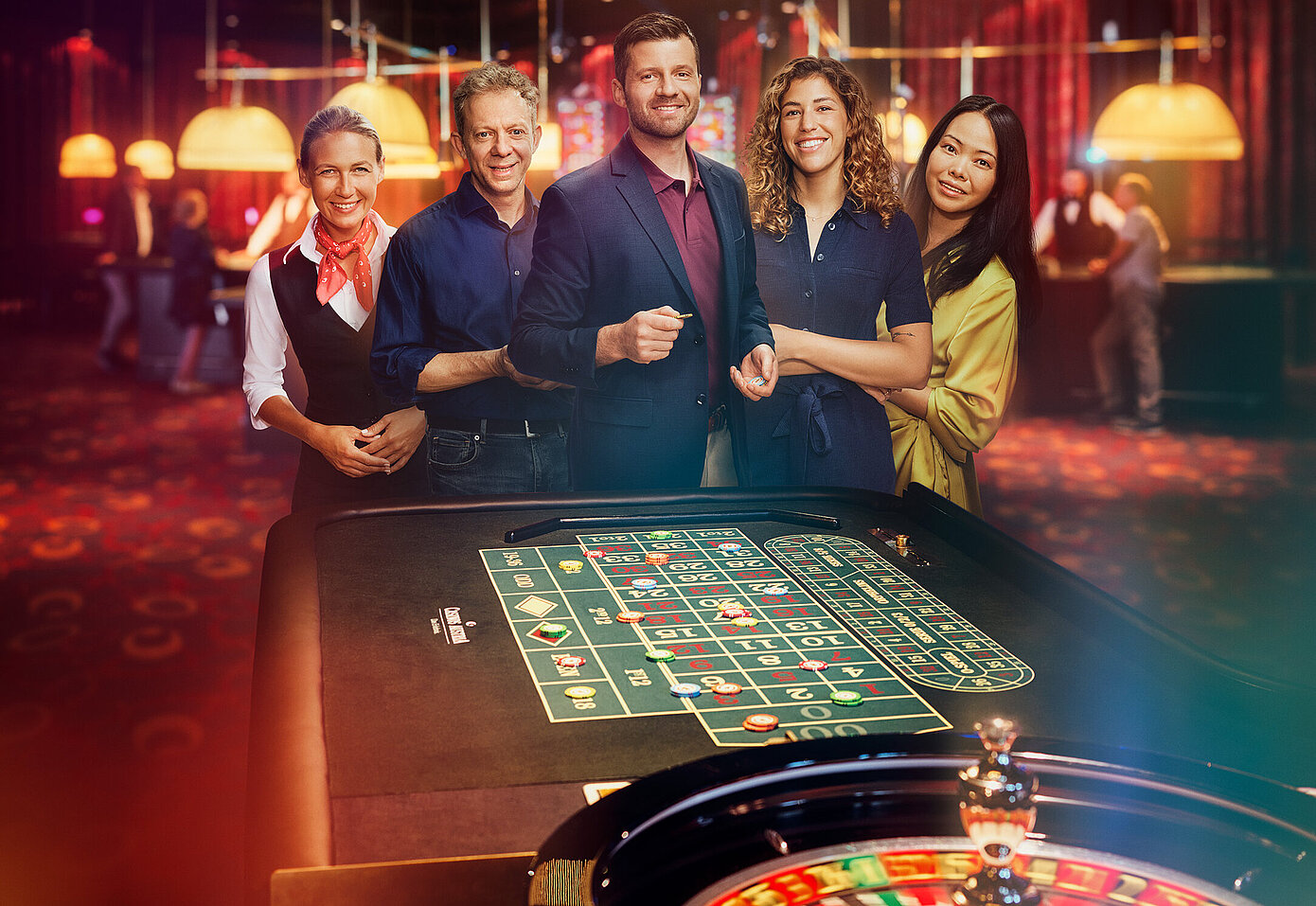 Croupière und Gäste-Gruppe stehen vor Roulette-Tisch