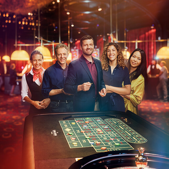 Croupière und Gäste-Gruppe stehen vor Roulette-Tisch