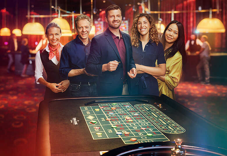 Croupière und Gäste-Gruppe stehen vor Roulette-Tisch