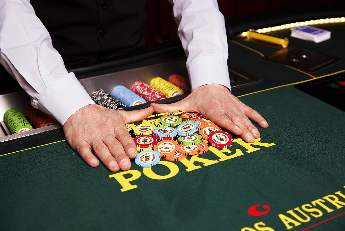 Croupier pushes forward chips from the poker pot with hands
