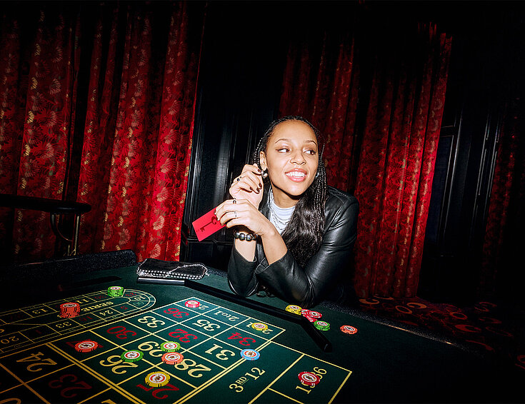 Casinos Austria Frau sitzt am Roulette Tisch mit RED Member Card