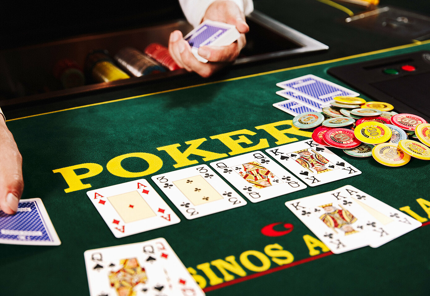 Dealer-Hände mit Poker-Karten und Pot am Poker-Tisch im Casino