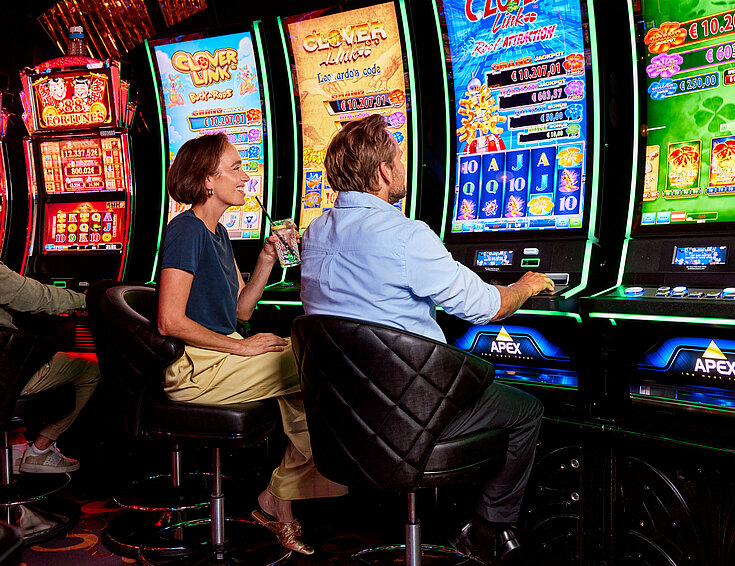 Frau und Mann vor Spielautomaten