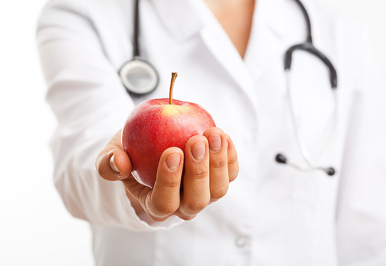 Ärztin hält einen Apfel in der Hand