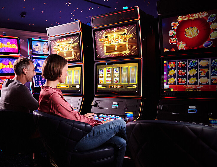 Ein Mann und eine Frau sitzen vor Spielautomaten