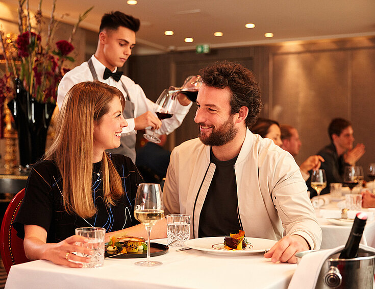 Casinos Austria Kellner bedient Paar im Casino Restaurant