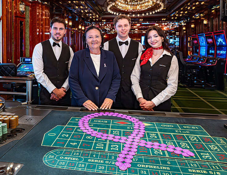 Pink Casino Night - Doris Kiefhaber Geschäftsführerin der Österr. Krebshilfe und der Aktion Pink Ribbon mit Croupière und Croupiers am Roulette-Tisch mit Pink Ribbon Symbol