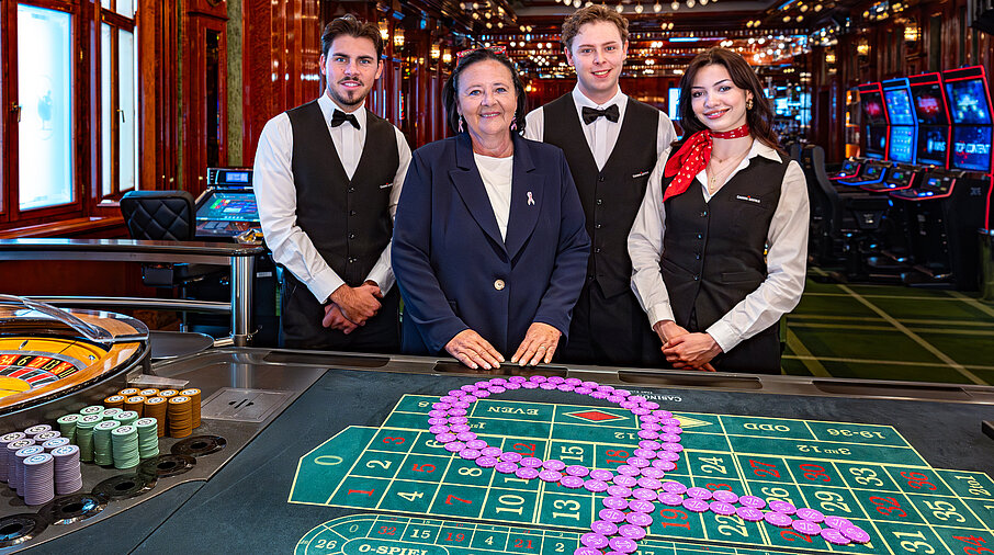 Pink Casino Night - Doris Kiefhaber Geschäftsführerin der Österr. Krebshilfe und der Aktion Pink Ribbon mit Croupière und Croupiers am Roulette-Tisch mit Pink Ribbon Symbol