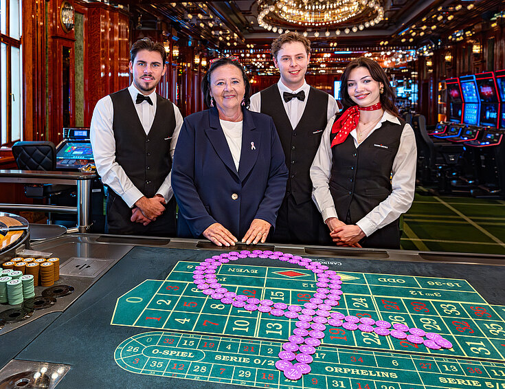 Pink Casino Night - Doris Kiefhaber Geschäftsführerin der Österr. Krebshilfe und der Aktion Pink Ribbon mit Croupière und Croupiers am Roulette-Tisch mit Pink Ribbon Symbol