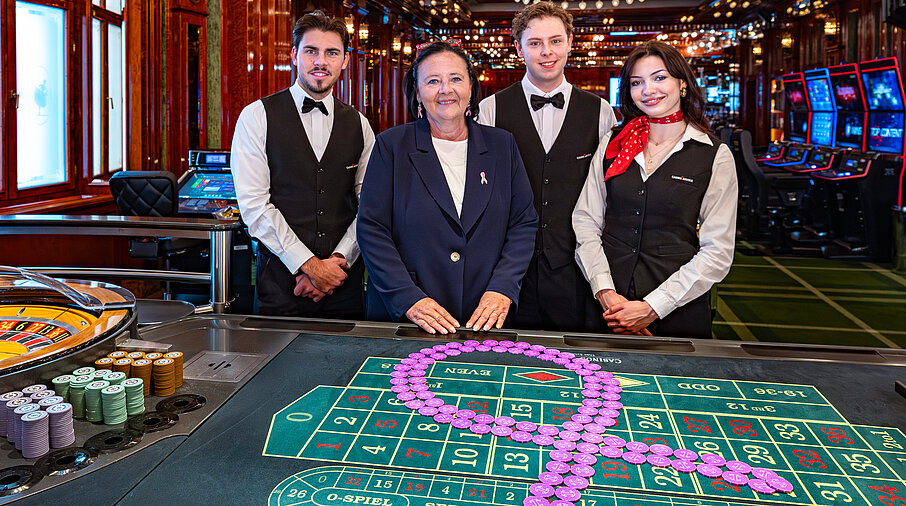 Pink Casino Night - Doris Kiefhaber Geschäftsführerin der Österr. Krebshilfe und der Aktion Pink Ribbon mit Croupière und Croupiers am Roulette-Tisch mit Pink Ribbon Symbol