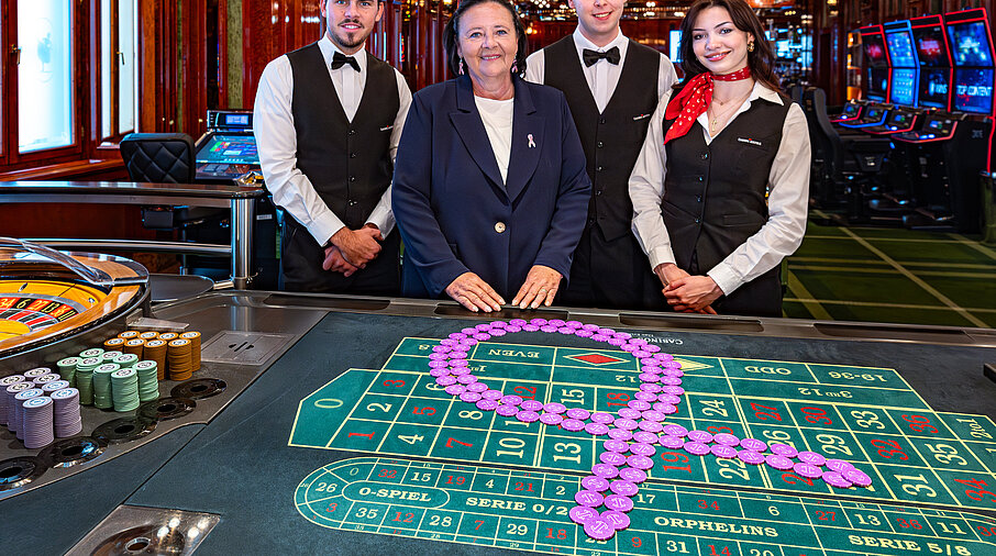 Pink Casino Night - Doris Kiefhaber Geschäftsführerin der Österr. Krebshilfe und der Aktion Pink Ribbon mit Croupière und Croupiers am Roulette-Tisch mit Pink Ribbon Symbol