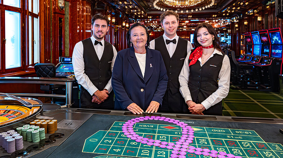 Pink Casino Night - Doris Kiefhaber Geschäftsführerin der Österr. Krebshilfe und der Aktion Pink Ribbon mit Croupière und Croupiers am Roulette-Tisch mit Pink Ribbon Symbol