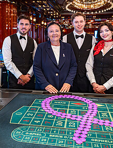 Pink Casino Night - Doris Kiefhaber Geschäftsführerin der Österr. Krebshilfe und der Aktion Pink Ribbon mit Croupière und Croupiers am Roulette-Tisch mit Pink Ribbon Symbol