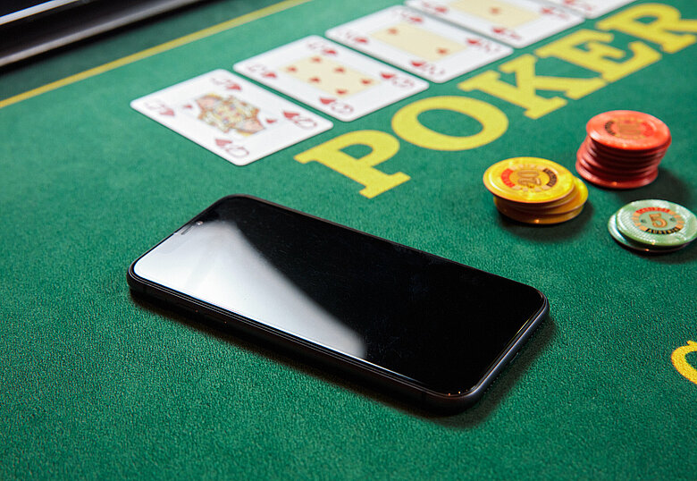 Poker Spieltisch Close-up mit Handy, Karten und Jetons