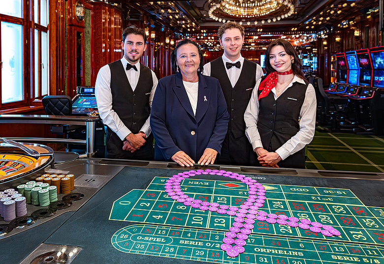 Pink Casino Night - Doris Kiefhaber Geschäftsführerin der Österr. Krebshilfe und der Aktion Pink Ribbon mit Croupière und Croupiers am Roulette-Tisch mit Pink Ribbon Symbol