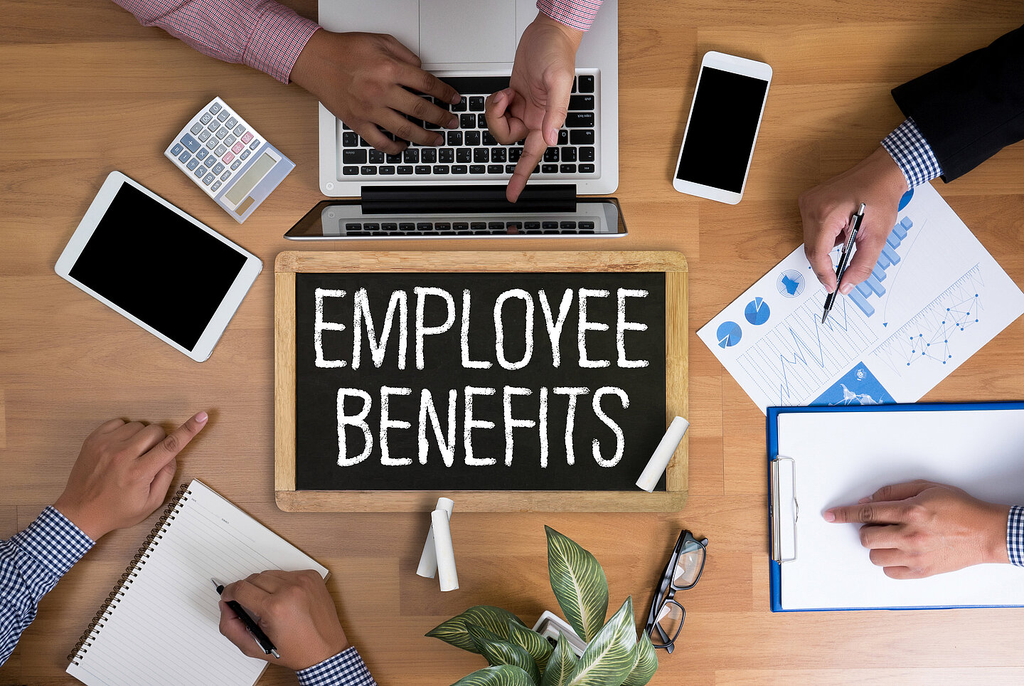 Tafel mit der Aufschrift Mitarbeiter Benefits auf Arbeitstisch mit Tablet und Smartphones