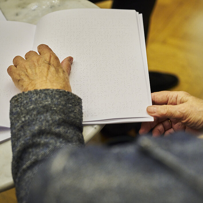 Inklusions-Projekt Burgtheater Person liest Werkeinführung Hamlet in Brailleschrift