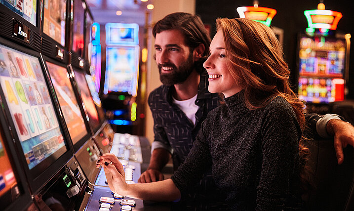 Frau und Mann spielen an den Spielautomaten im Casino