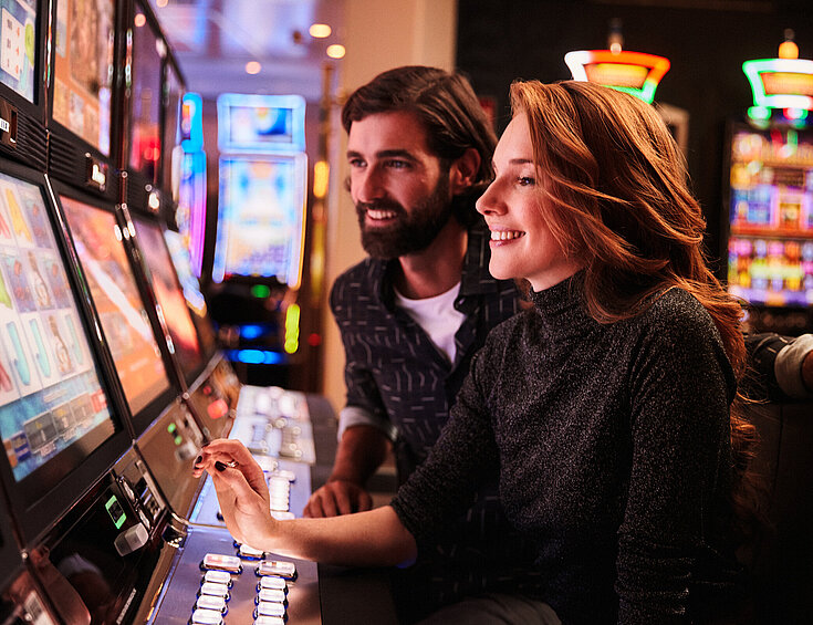 Casinos Austria Frau und Mann spielen an den Spielautomaten im Casino