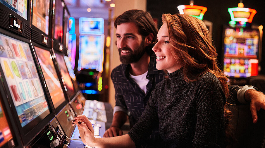 Frau und Mann spielen an den Spielautomaten im Casino