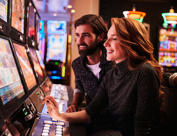 Frau und Mann spielen an den Spielautomaten im Casino