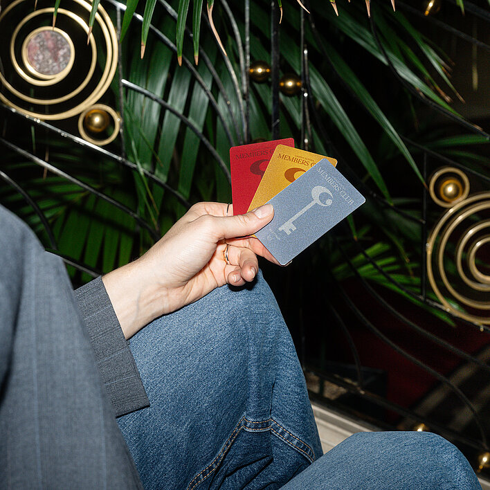 Frau sitzt mit Member Club Cards auf der Stiege