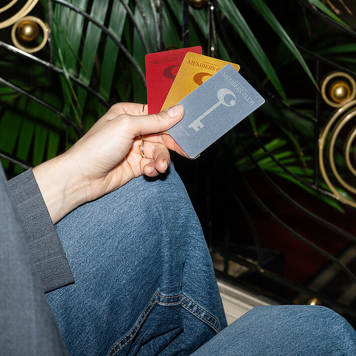 Frau sitzt mit Member Club Cards auf der Stiege