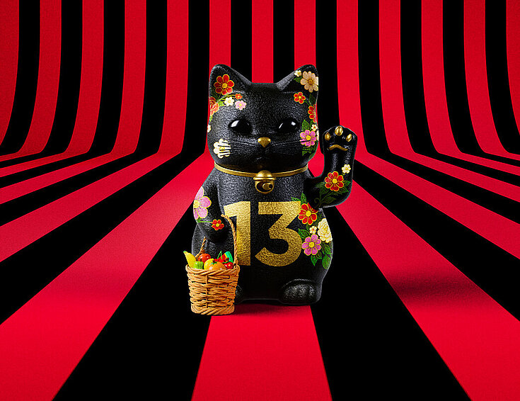 13er Glückskatze mit Blumen und Korb auf rot-schwarz-gestreiftem Hintergrund