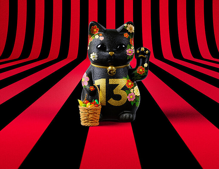 13er Glückskatze mit Blumen und Korb auf rot-schwarz-gestreiftem Hintergrund