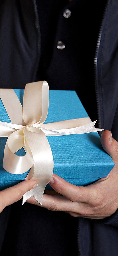 Frau übergibt blaues Geschenkspaket an Mann