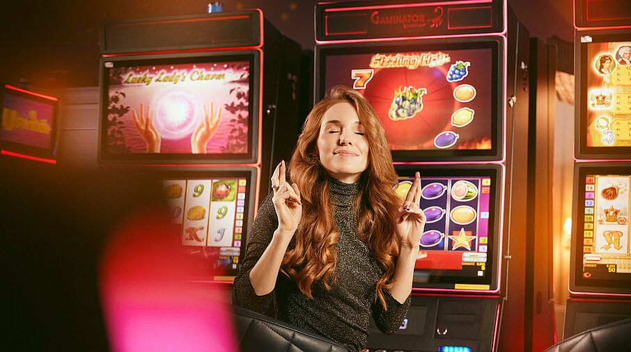 Dame mit gekreuzten Fingern vor den Spielautomaten