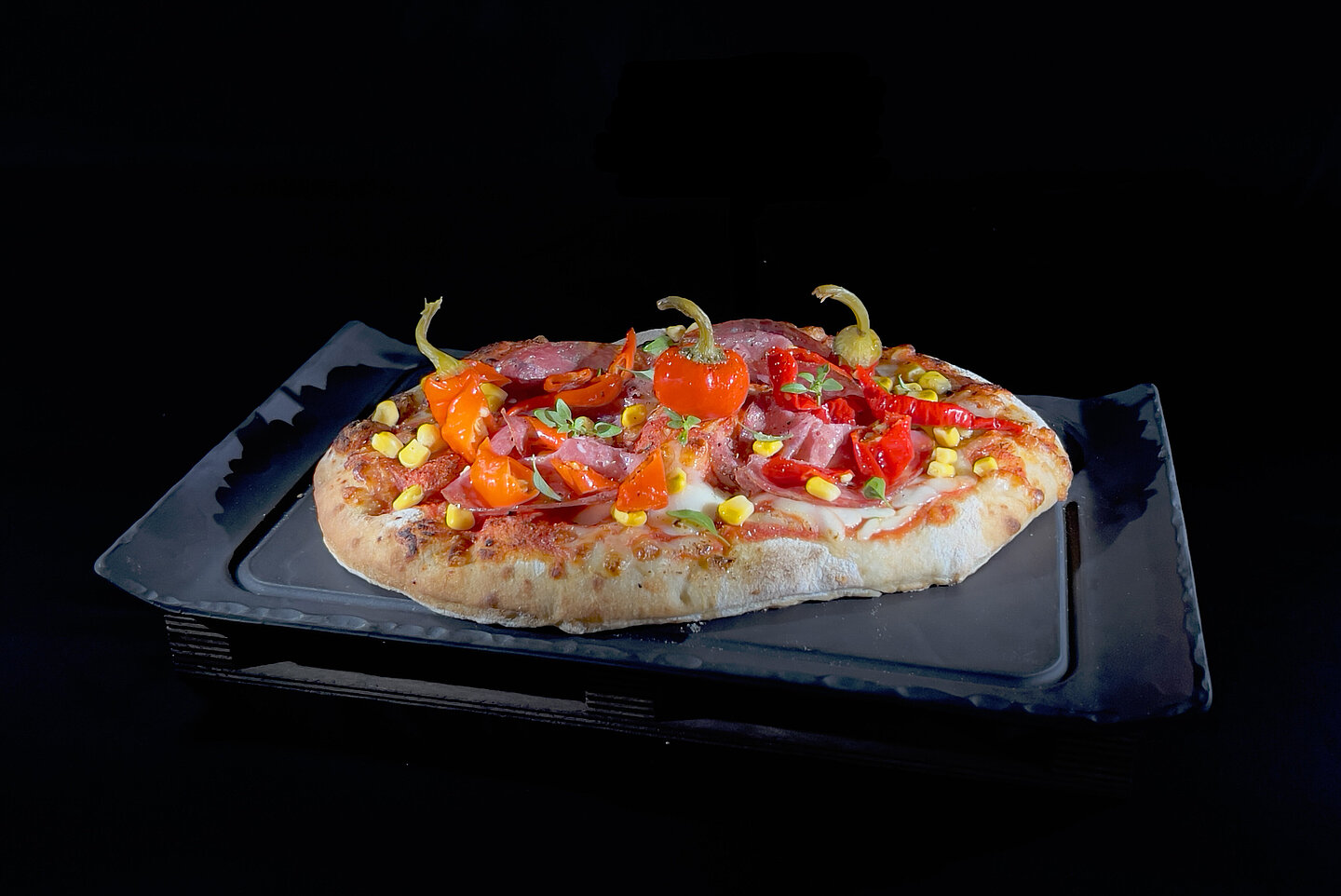 Pinsa Salami auf schwarzem Teller und Hintergrund